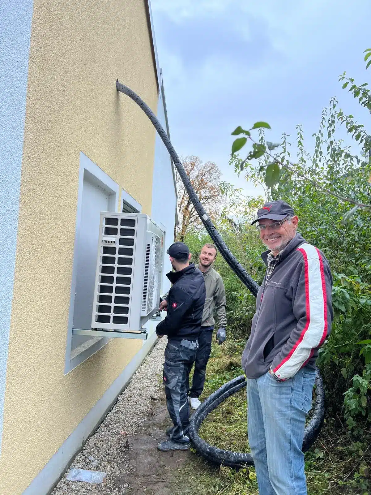 Professionelle Klimaanlageninstallation München Technikerteam bei der Installation einer Klimaanlage an der Außenwand eines Gebäudes in München