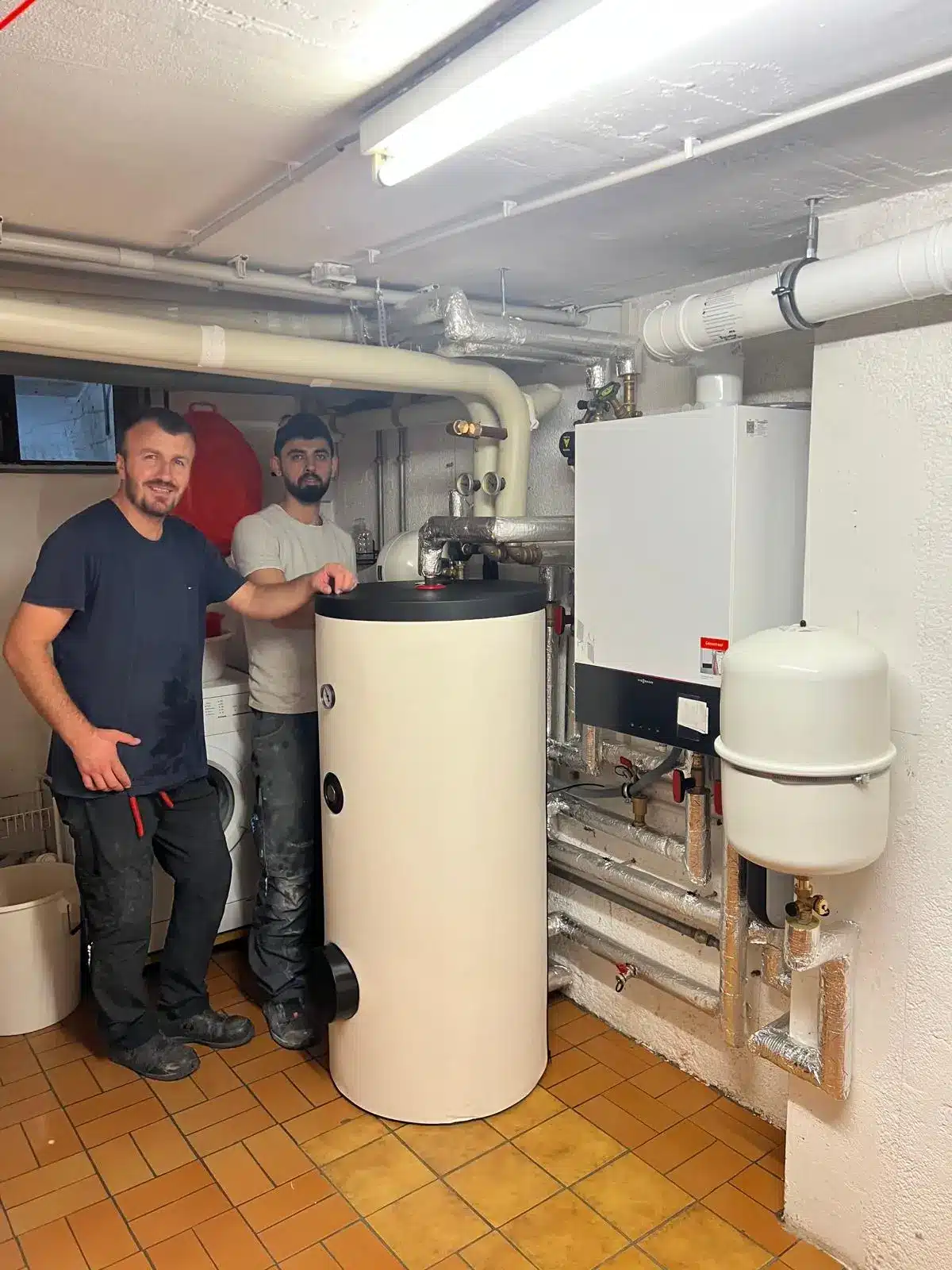 Erfolgreiche Heizungsinstallation München Zwei Techniker stehen stolz neben einer neu installierten Heizanlage in München
